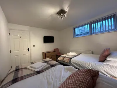 a bedroom with two beds and a tv and a window at Lovely refurbished apartments, Morecambe Promenade in Morecambe