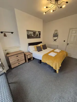 a bedroom with two beds and a dresser and a couch at Lovely refurbished apartments, Morecambe Promenade in Morecambe
