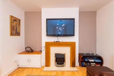 a living room with a fireplace with a tv above it at The Chestnut - Liverpool City - L7 in Liverpool
