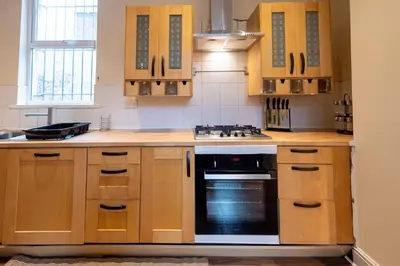 a kitchen with wooden cabinets and a stove top oven at The Chestnut - Liverpool City - L7 in Liverpool