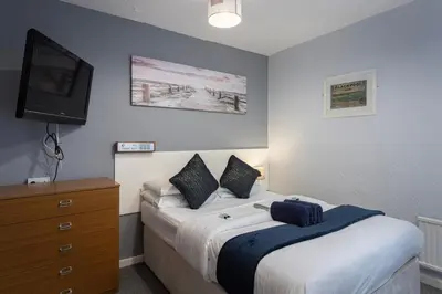 a bedroom with a bed and a dresser with a television at Royal Oakwell Hotel in Blackpool
