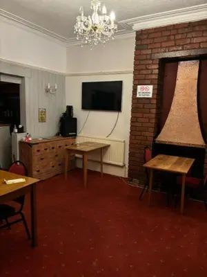a living room with a table and a tv and a room with a fireplace at Argyll guest house in Blackpool