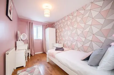 a bedroom with a white bed with a geometric wall at *Superb Location* Large 4 Bedroom City Centre Home in Liverpool