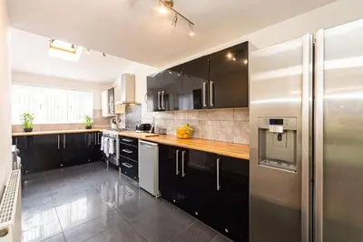 a kitchen with black cabinets and a stainless steel refrigerator at *Superb Location* Large 4 Bedroom City Centre Home in Liverpool