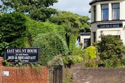 a sign on a brick wall in front of a house at East Mount House in Barrow in Furness