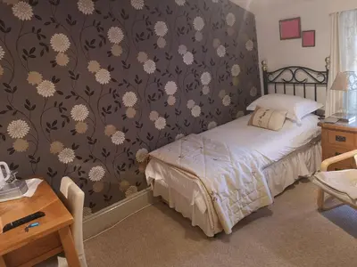 a bedroom with a bed with a floral wallpaper at East Mount House in Barrow in Furness