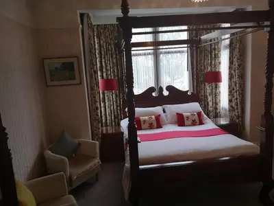 a bedroom with a canopy bed and a chair at East Mount House in Barrow in Furness
