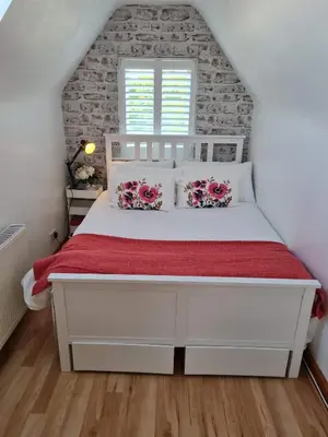 a bedroom with a white bed with a red bedspread at Brenda & Petes in Birkenhead