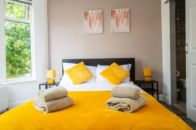a bedroom with a yellow bed with towels on it at Five Seasons Liverpool City - Modern Studios near Anfield in Liverpool