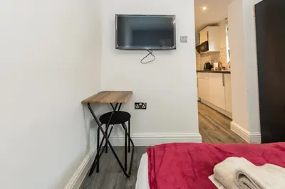a room with a table and a television on a wall at Five Seasons Liverpool City - Modern Studios near Anfield in Liverpool