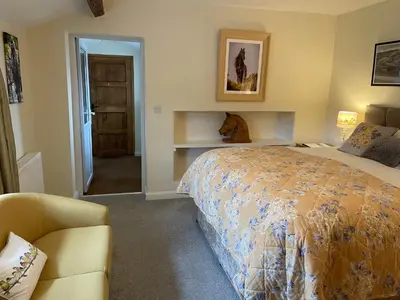 a bedroom with a bed and a chair and a door at Greenbank Farm House in Cartmel
