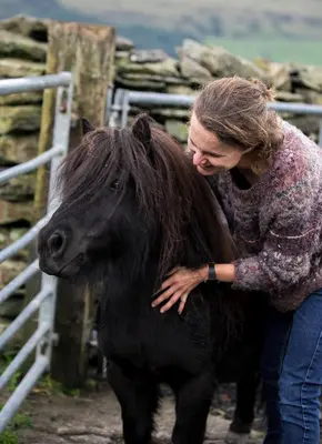 a woman standing next to a black horse at Greenbank Farm House in Cartmel