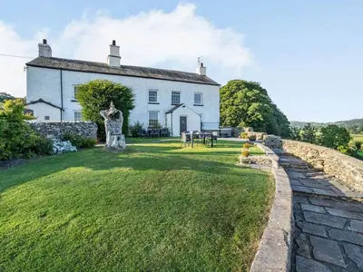 a large white house with a statue in front of it at Greenbank Farm House in Cartmel