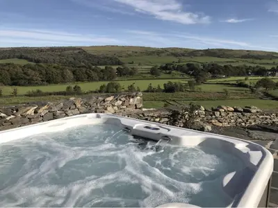 a jacuzzi tub with a stone wall at Greenbank Farm House in Cartmel