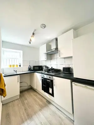 a kitchen with white cabinets and a black counter top at The County Staycation in Liverpool