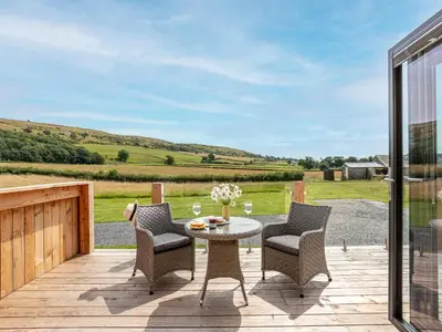 a patio with a table and chairs on a wooden deck at Low Longlands in Cartmel