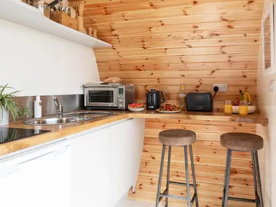a kitchen with wooden walls and stools in a tiny house at Low Longlands in Cartmel