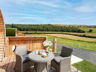 a patio with a table and chairs on a deck at Low Longlands in Cartmel