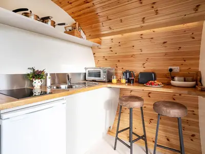 a kitchen with wooden walls and a counter with stools at Middle Longlands in Cartmel