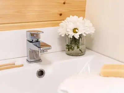 a vase of white flowers sitting on a bathroom sink at Middle Longlands in Cartmel