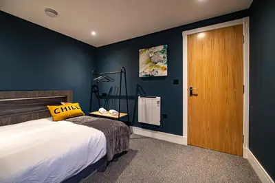 a bedroom with blue walls and a bed with a yellow pillow at The Nest - Luxury 16 person Apt w jacuzzi & parking in Blackpool