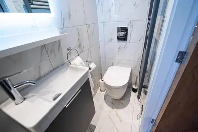 a white bathroom with a toilet and a sink at The Nest - Luxury 16 person Apt w jacuzzi & parking in Blackpool