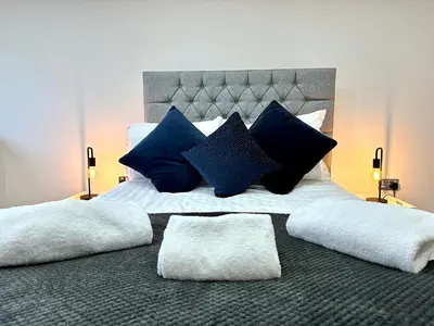 a large bed with blue and white pillows on it at York Street Apartments by Blackpool Service Apartments in Blackpool