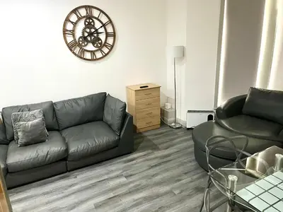 a living room with a couch and a clock on the wall at York Street Apartments by Blackpool Service Apartments in Blackpool
