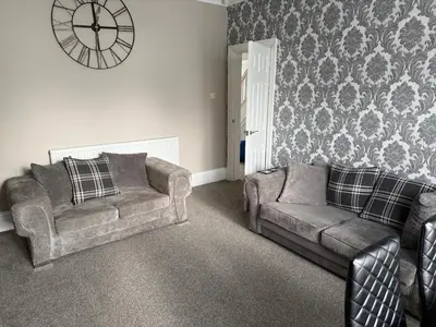a living room with two couches and a clock on the wall at Pleasure Beach View in Blackpool