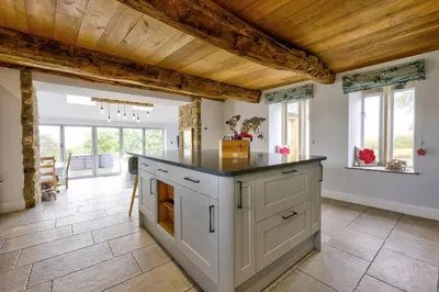 a kitchen with an island in a room with windows at Swans Farm in Lancaster