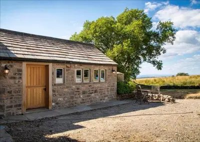 a stone cottage with a bench and a table at Swans Farm in Lancaster