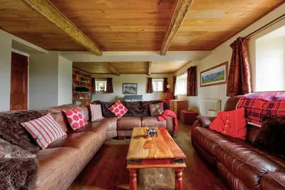 a living room with leather couches and a wooden ceiling at Swans Farm in Lancaster