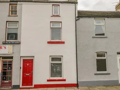 a white house with red doors on a street at Harbour Retreat in Millom