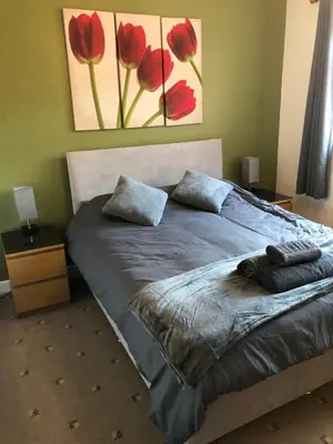 a bedroom with a bed with red flowers on the wall at 2 Bedroom Bungalow in Mawdesley