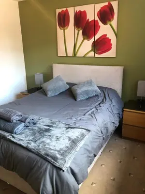 a bedroom with a bed with red flowers on the wall at 2 Bedroom Bungalow in Mawdesley