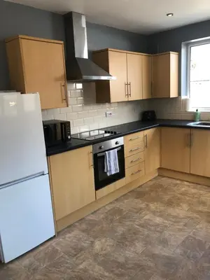 a kitchen with wooden cabinets and a white refrigerator at 2 Bedroom Bungalow in Mawdesley