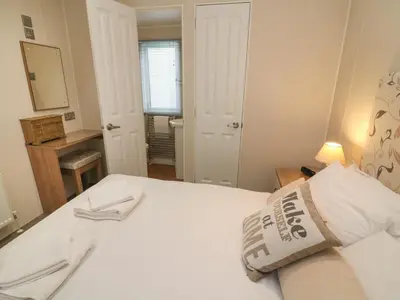 a bedroom with a white bed and a mirror at Waterside Lodge in Carnforth