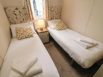 two twin beds in a room with a window at Waterside Lodge in Carnforth
