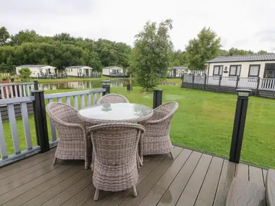 a patio with a table and chairs on a deck at Waterside Lodge in Carnforth