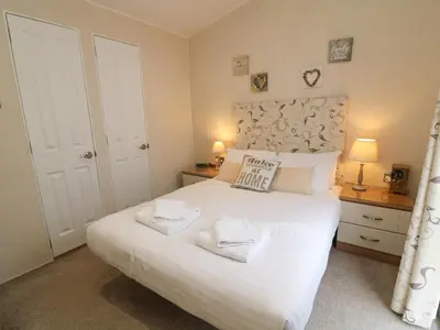 a bedroom with a large white bed with two towels at Waterside Lodge in Carnforth