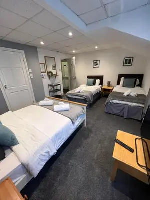 a room with three beds and a table at The Wilton Hotel in Blackpool