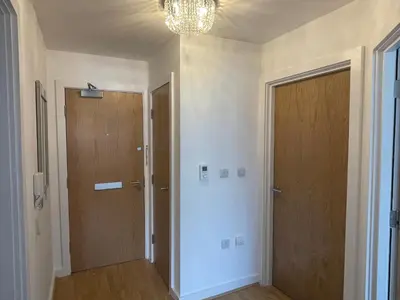 a hallway with two wooden doors and a chandelier at Moda Wigan - Stylish 2 Bed Apartment Central Wigan in Wigan