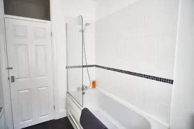 a white bathroom with a tub and a shower at The Little Bear Apartment Birkdale Village in Southport