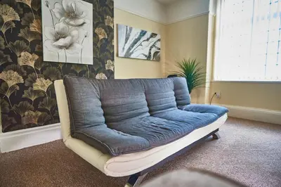 a blue couch in a living room with a window at The Little Bear Apartment Birkdale Village in Southport