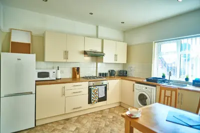 a kitchen with white appliances and a table and a window at The Little Bear Apartment Birkdale Village in Southport