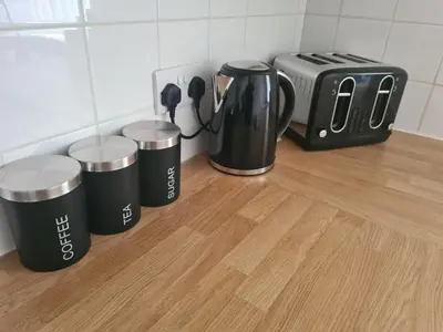 a counter with three coffee cups and a toaster at The Little Bear Apartment Birkdale Village in Southport