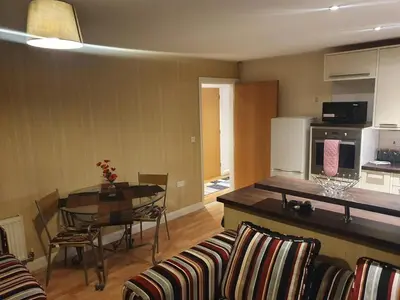 a kitchen and a living room with a table and chairs at Two Bedroom Apartment, Free parking, Close to UCLAN and free WIFI in Preston
