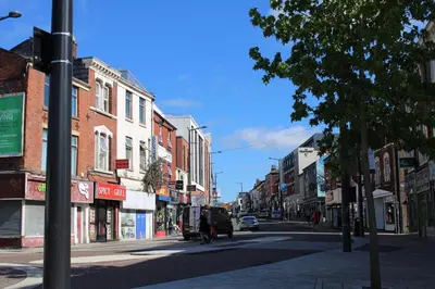 a city street with buildings and a person walking down the street at Two Bedroom Apartment, Free parking, Close to UCLAN and free WIFI in Preston