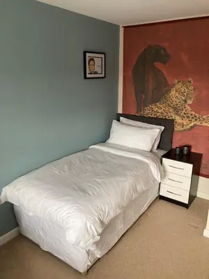 a bedroom with a white bed with a painting on the wall at Cheerful Home FOR FOOTBALL, DOCKS AND CITY CENTRE in Liverpool