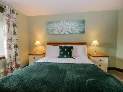 a bedroom with a green bed with two lamps at Ewedale Farm in Ulverston